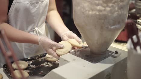 woman filling donuts with frosting at a donut shop