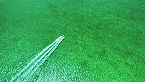 top-down aerial view of boat motoring away in turquoise bahamas flat