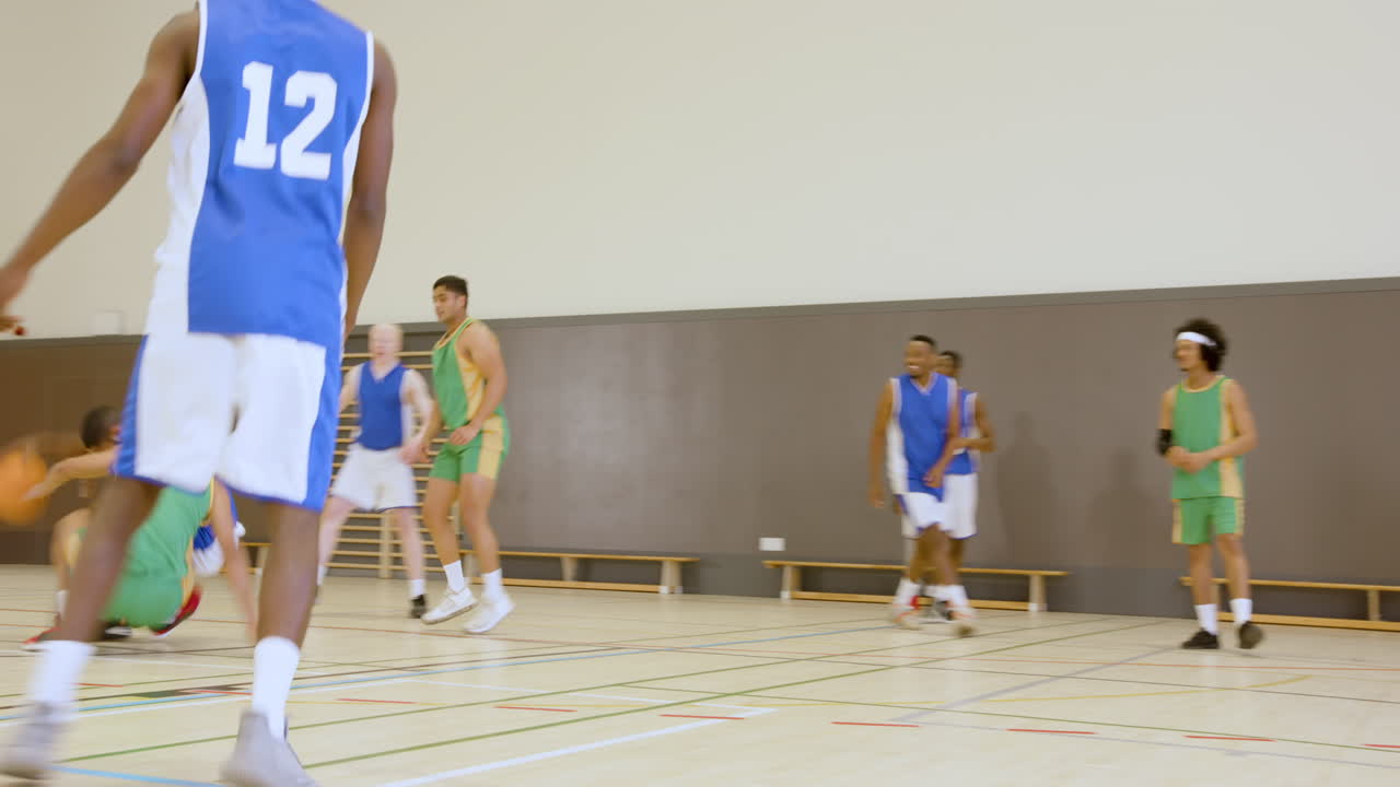 Basketball players helping teammates up on court during friendly game