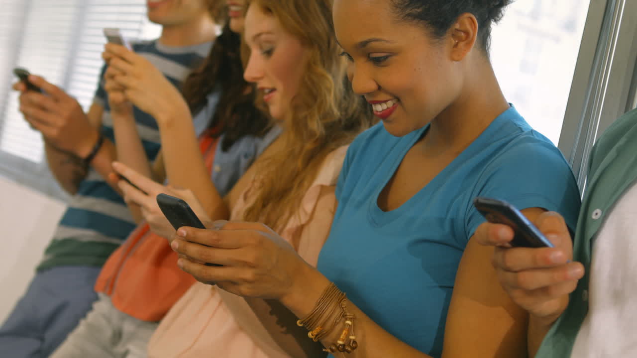 estudiantes usando sus teléfonos inteligentes en una fila