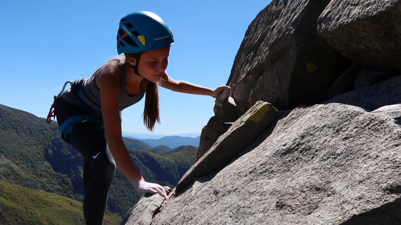 Young person rock climbing outdoors on a sunny day