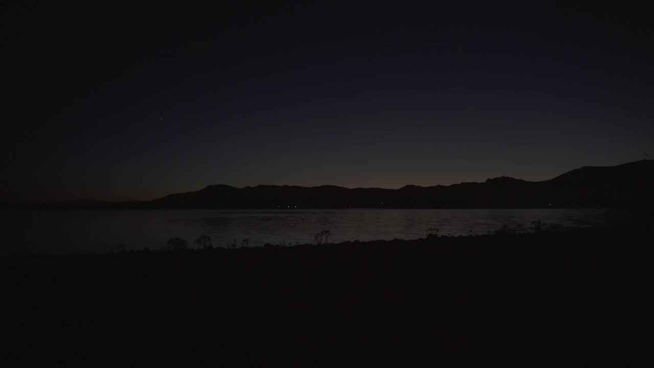 Vista notturna serena di un lago calmo e montagne lontane