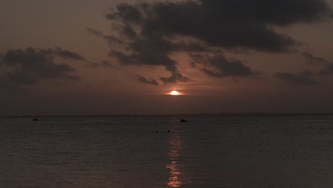 people on jet skis in front of dark zanzibar sunset glow on michamvi kae beach