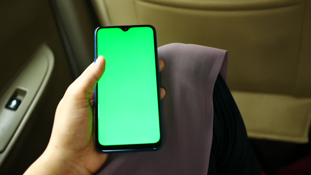 mujeres con la mano navegando por un teléfono inteligente con pantalla verde en un coche