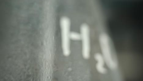 close-up of water droplets on a glass container labeled with h2o