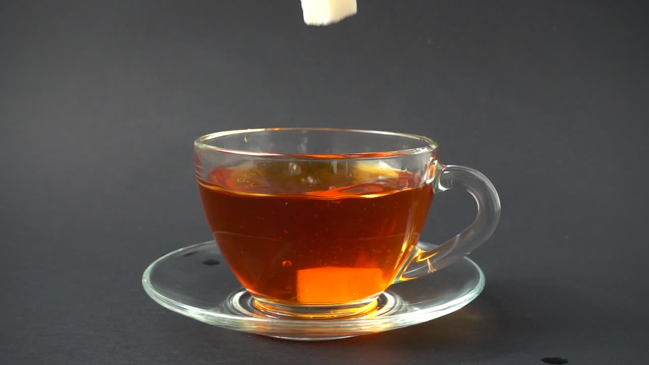 Zucchero cade in una tazza con tè. Movimento rallentato.