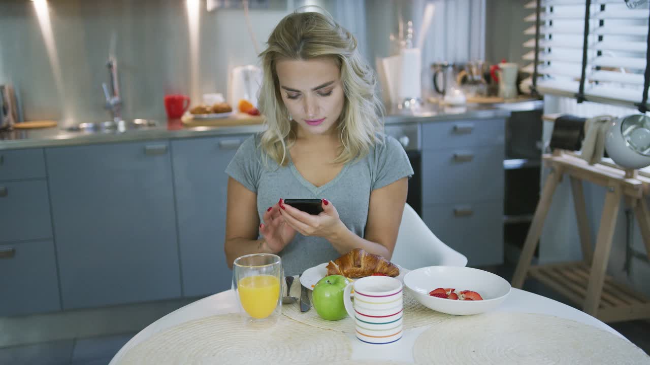 mujer usando un teléfono inteligente durante el desayuno