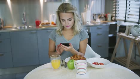 Mujer-Con-Smartphone-Durante-El-Desayuno