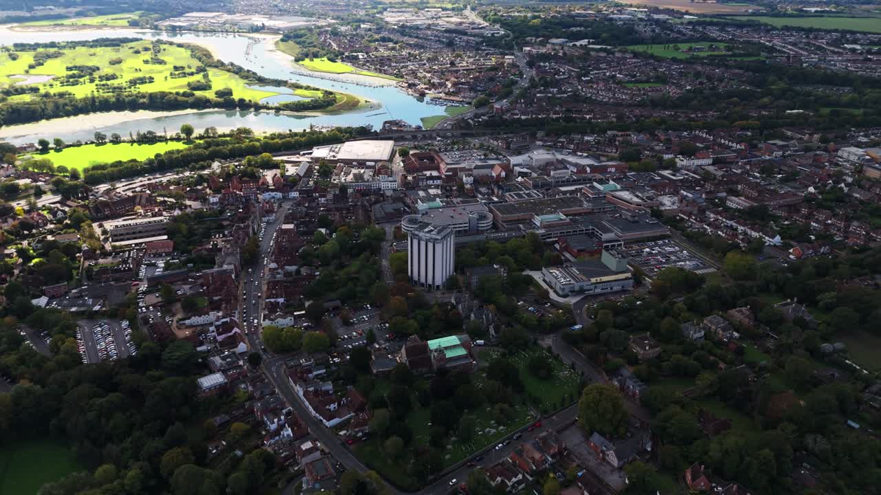 Aerial drone flies over towards Fareham town centre with river in the background, capturing roads, cars, and autumn trees bathed in warm golden sunset light across the scenic English landscape