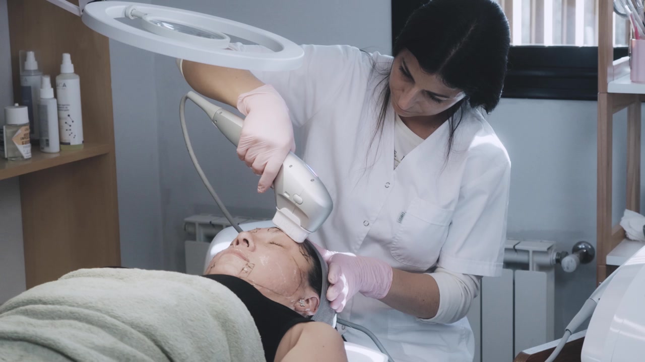 Esteticista profissional realizando tratamento de firmeza da pele facial em clínica