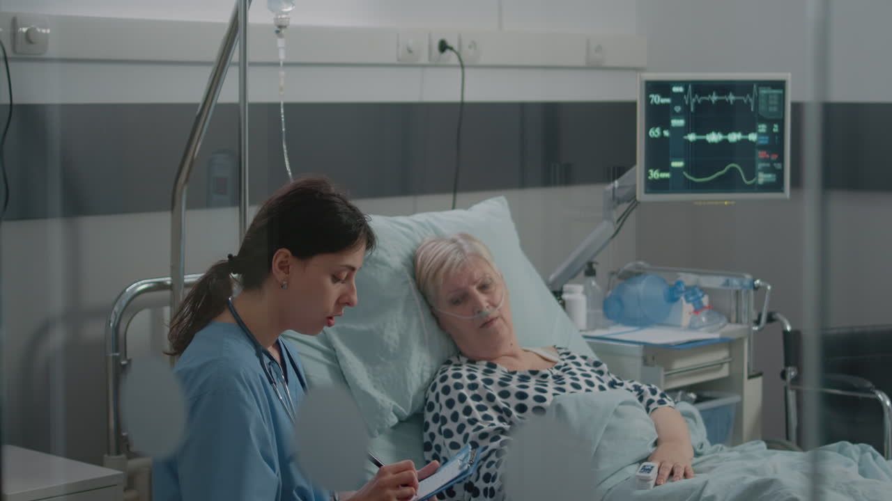 Medical assistant doing checkup visit for patient in hospital ward bed