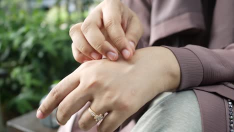 young women suffering from itching skin sitting on park ,