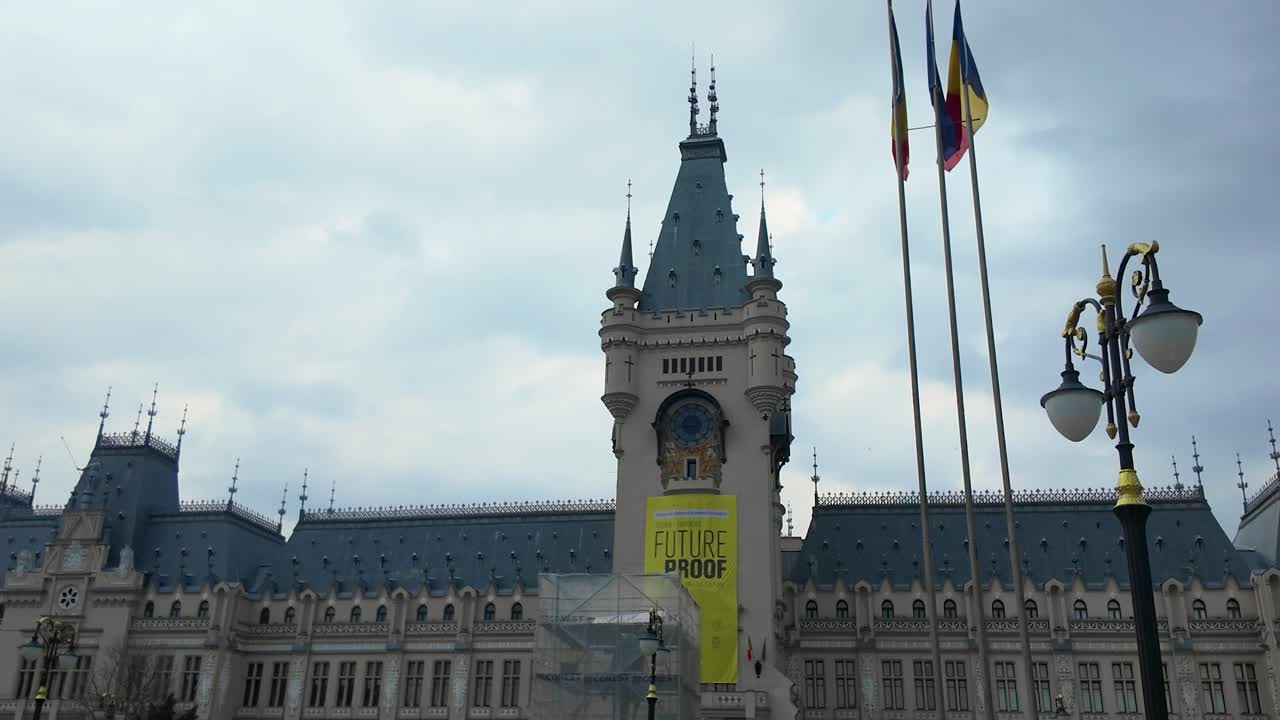 Vista en hyperlapse del Palacio de la Cultura en Iași, Rumanía, enfocándose en la torre del reloj y la fachada bajo un cielo nublado