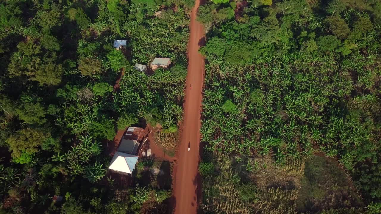 Drone Shot Of A Motorcycle Driving On A Dusty Street In Uganda