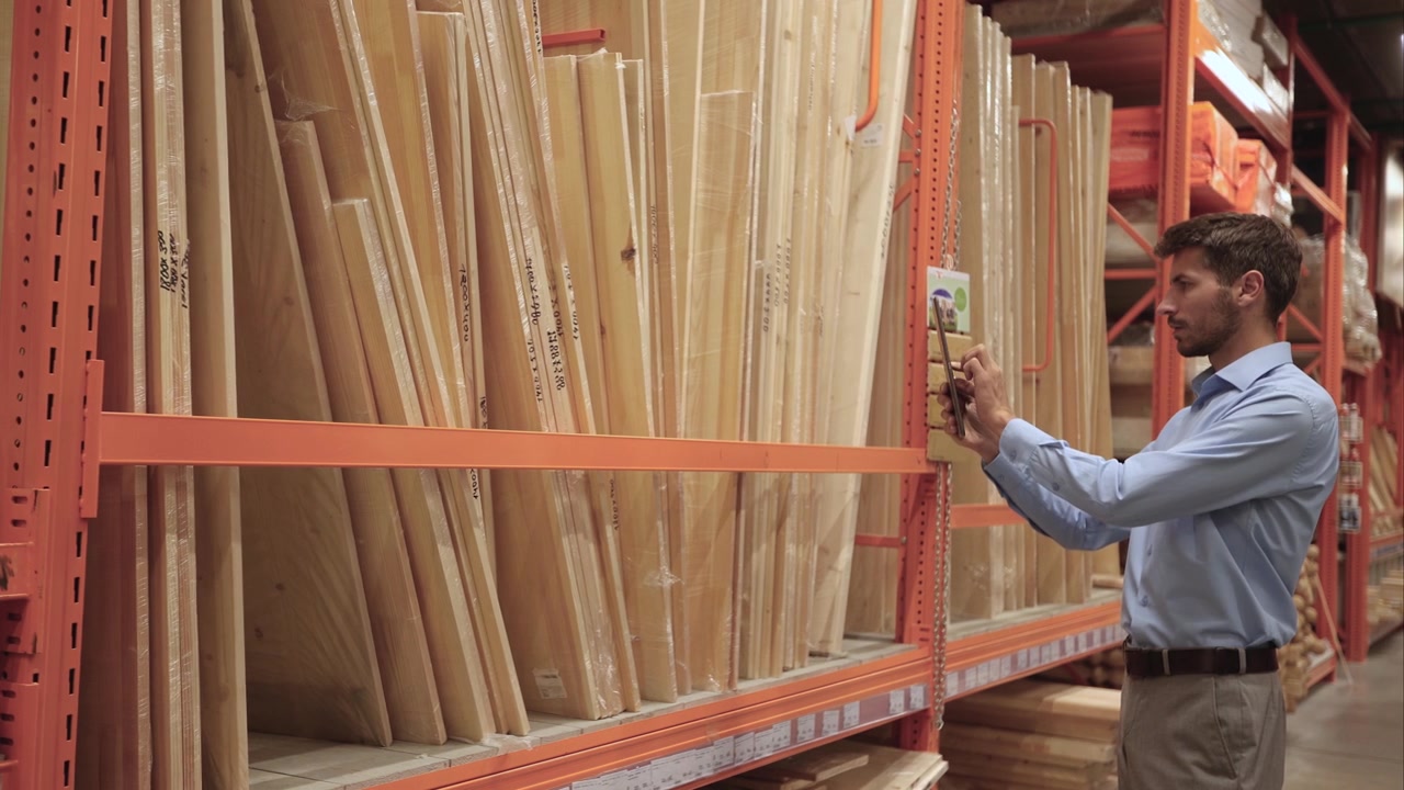 Man Scanning Wooden Boards with Digital Tablet in Warehouse