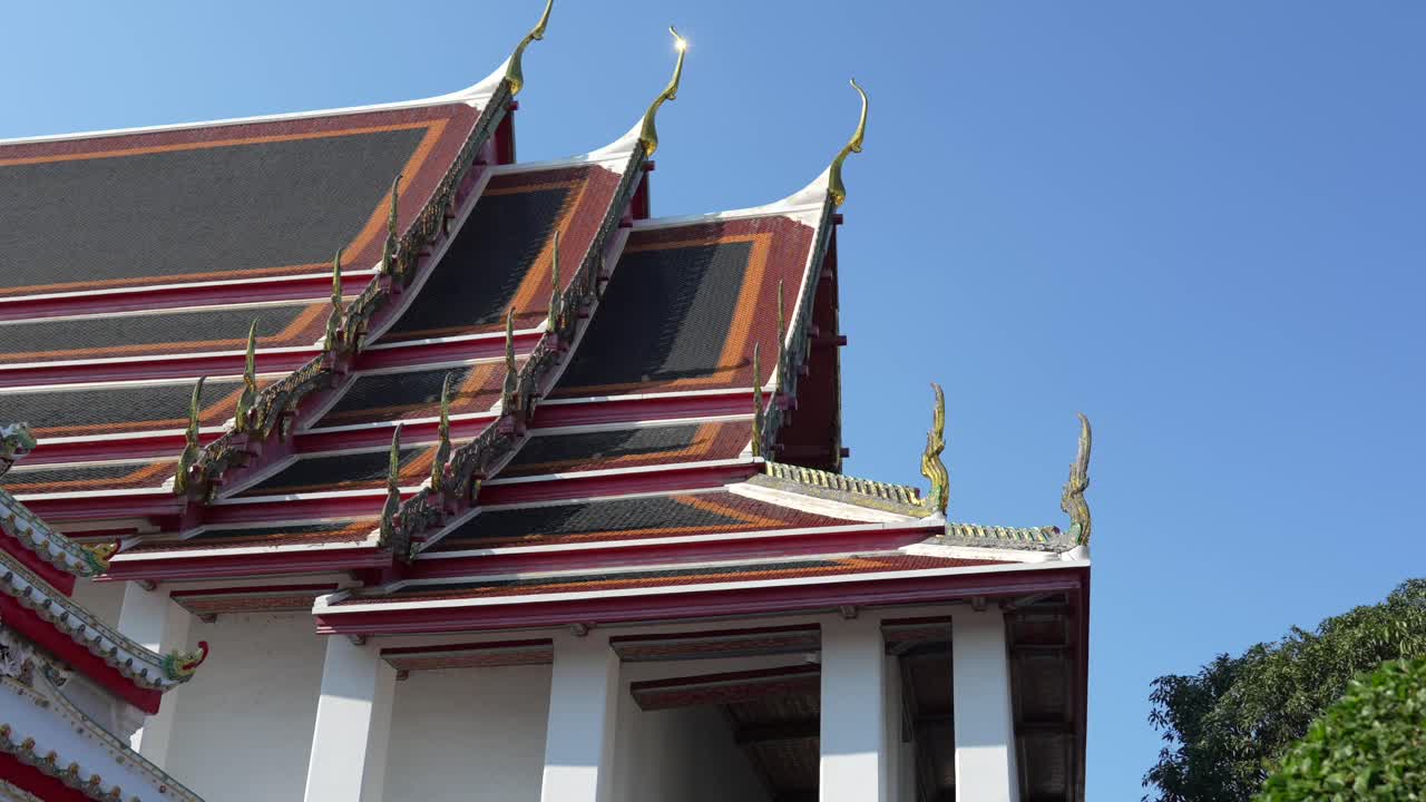 Wat Pho temple rooftops in Bangkok, Thailand, showing traditional Thai architecture details and golden chofas under a clear blue sky, highlighting a prominent cultural landmark