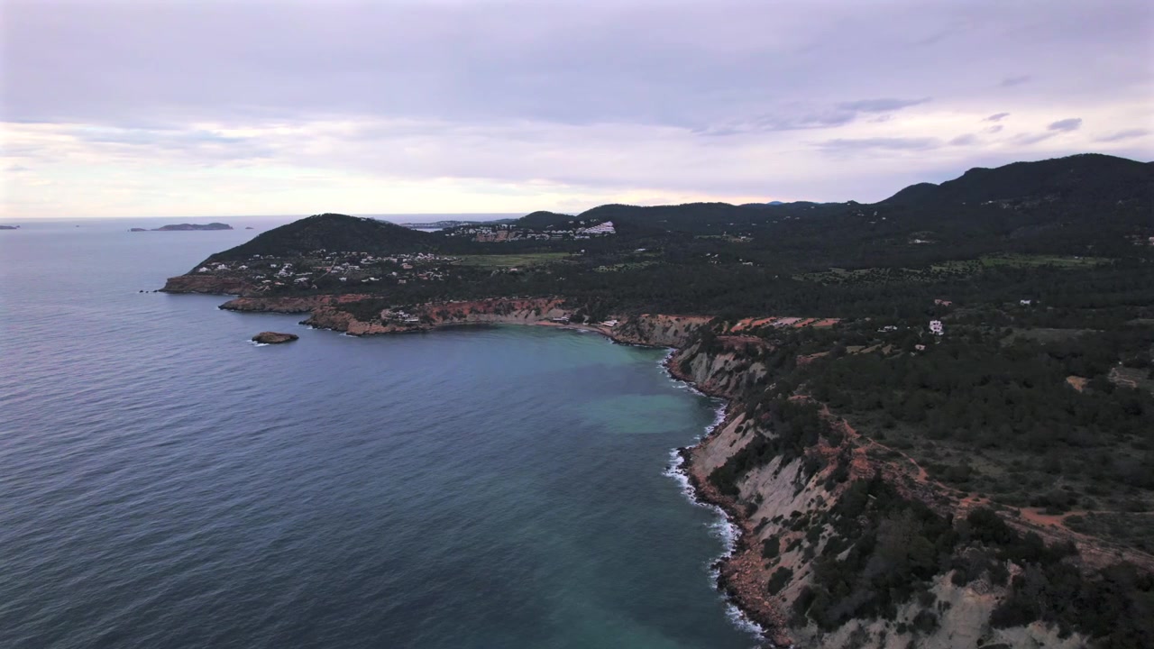 Ripresa aerea in 4K con drone di Cap Blanc a Ibiza, Spagna. Scogliere rocciose spettacolari, acque cristalline del Mediterraneo e vista verso l'iconica isola di Es Vedrà creano un paesaggio costiero mozzafiato