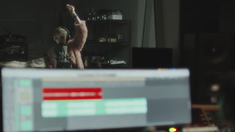 female musician singing during recording session with sound engineer in studio