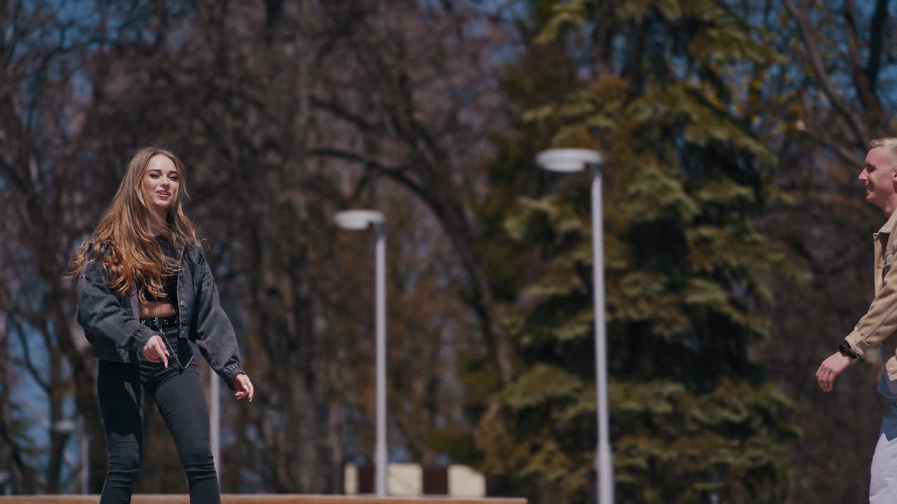 Happy teenagers having a date in the park. Boyfriend carrying his girlfriend and circling with her. Cheerful young couple having fun together outdoors.
