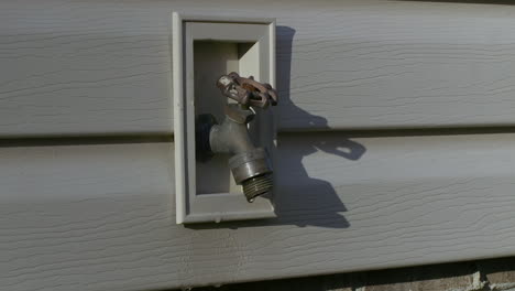 freshwater spigot on side of house, with water dripping out slowly