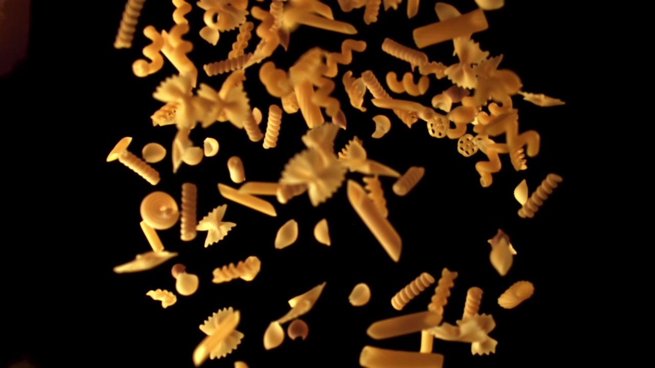 Various Shapes of Pasta Falling in Slow Motion on a Black Background