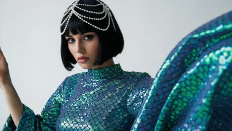 a stunning model adorned with a pearl headpiece showcases a shimmering scales-patterned outfit, capturing the essence of glamour and high fashion in captivating detail