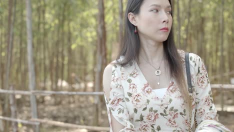 a beautiful asian woman sits on a park bench in a very somber and lonely mood