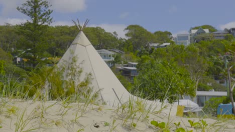 teepee sculpture amidst beach vegetation and houses