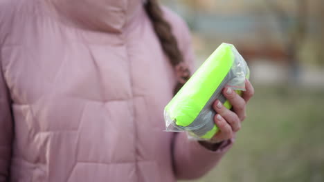 close-up of person wearing light purple quilted winter jacket with braid partially visible, standing outdoors in blurred park background, representing cold weather clothing,and seasonal fashion