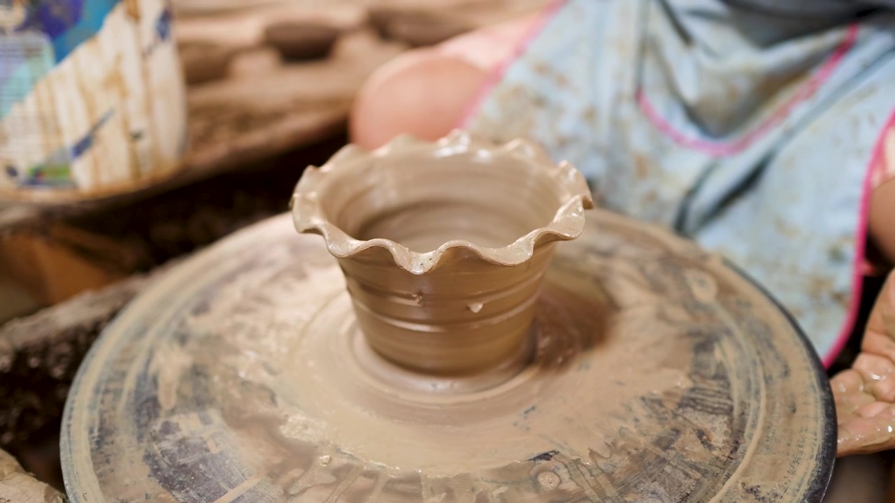 Primo piano delle mani di un artigiano che modellano argilla di terracotta su un tornio in un laboratorio