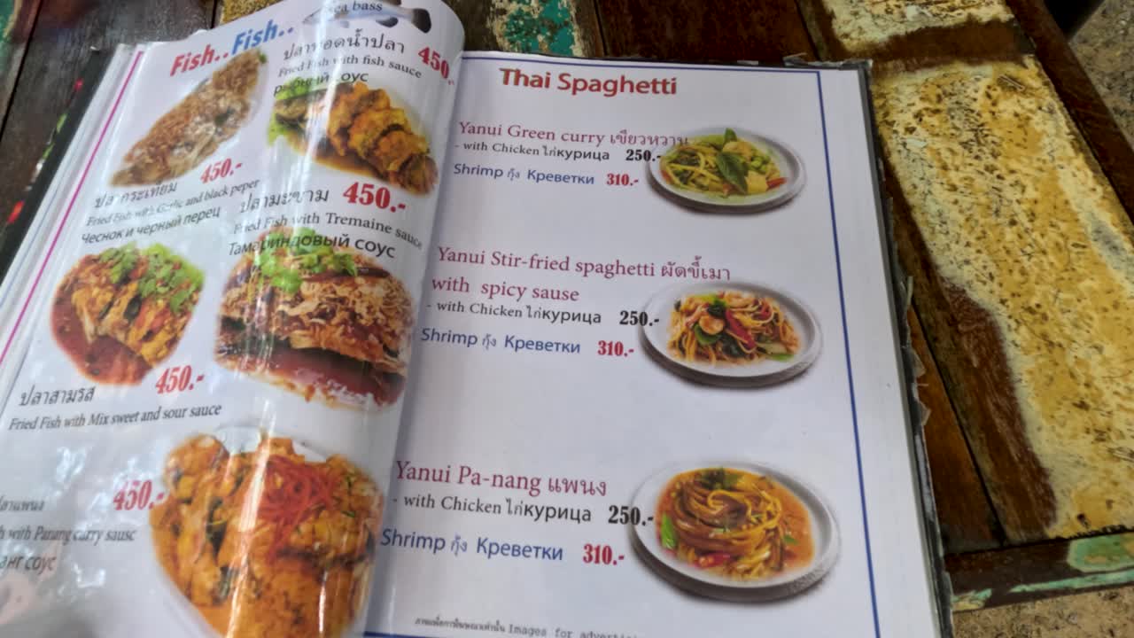 una mirada detallada a un menú de restaurante en phuket, tailandia, que muestra varios platos internacionales con imágenes vibrantes y precios claros