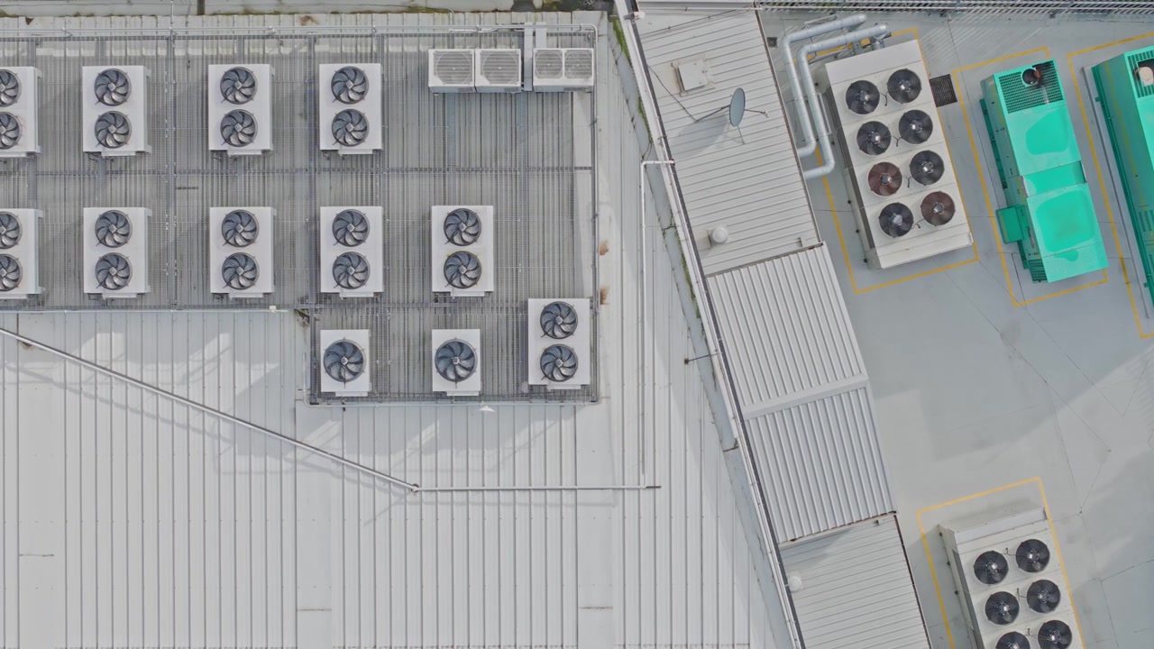 Drone footage reveals a high-security data center rooftop with industrial HVAC units, cooling towers, and ventilation. Clean, geometric layout in bright daylight with no people visible.