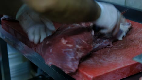 cuts raw meat with knife