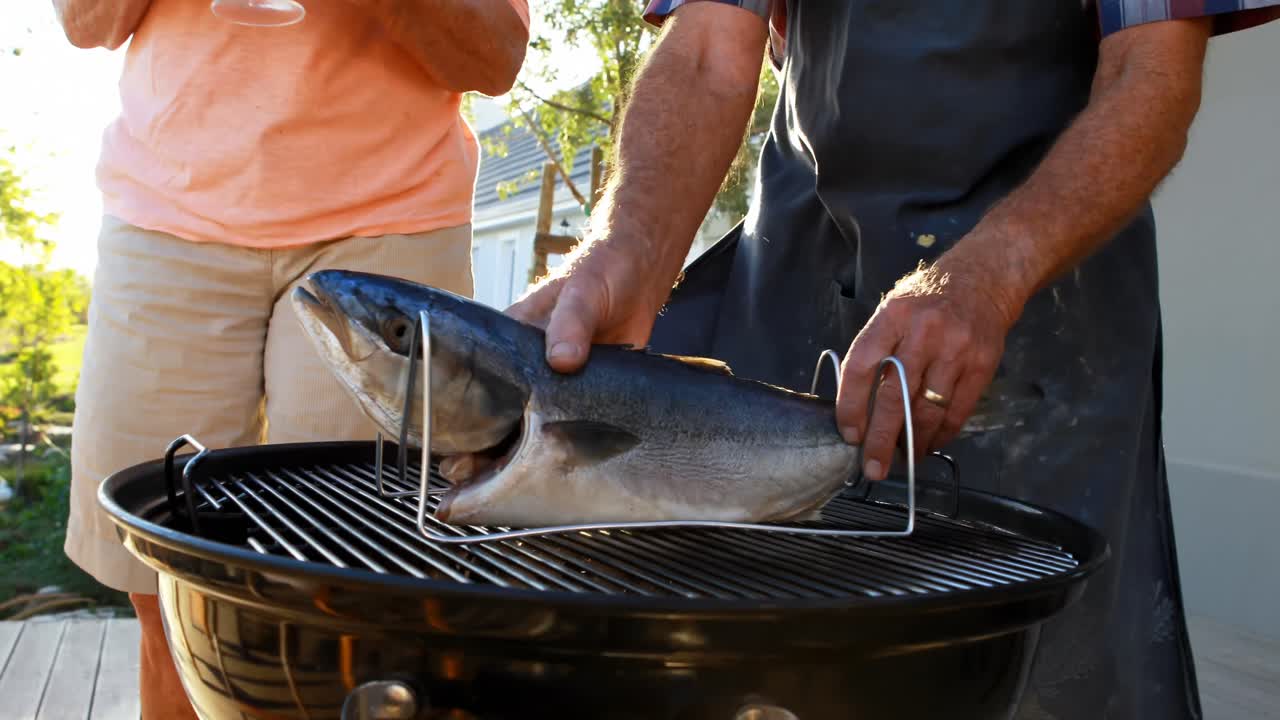 Coppia anziana che prepara pesce sul barbecue 4k