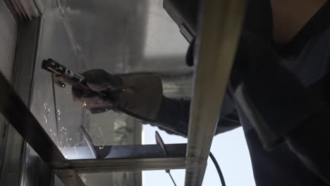 slow motion view from below of stick welder working on metal framework