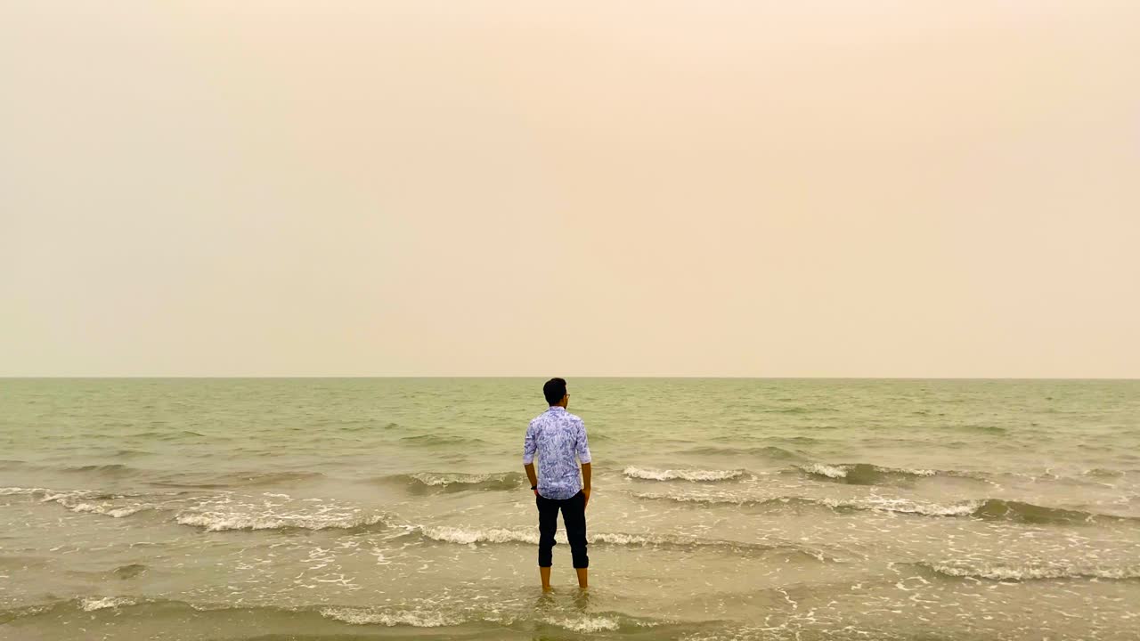 Lonely man standing on beach shore, staring at calm sea. Me time