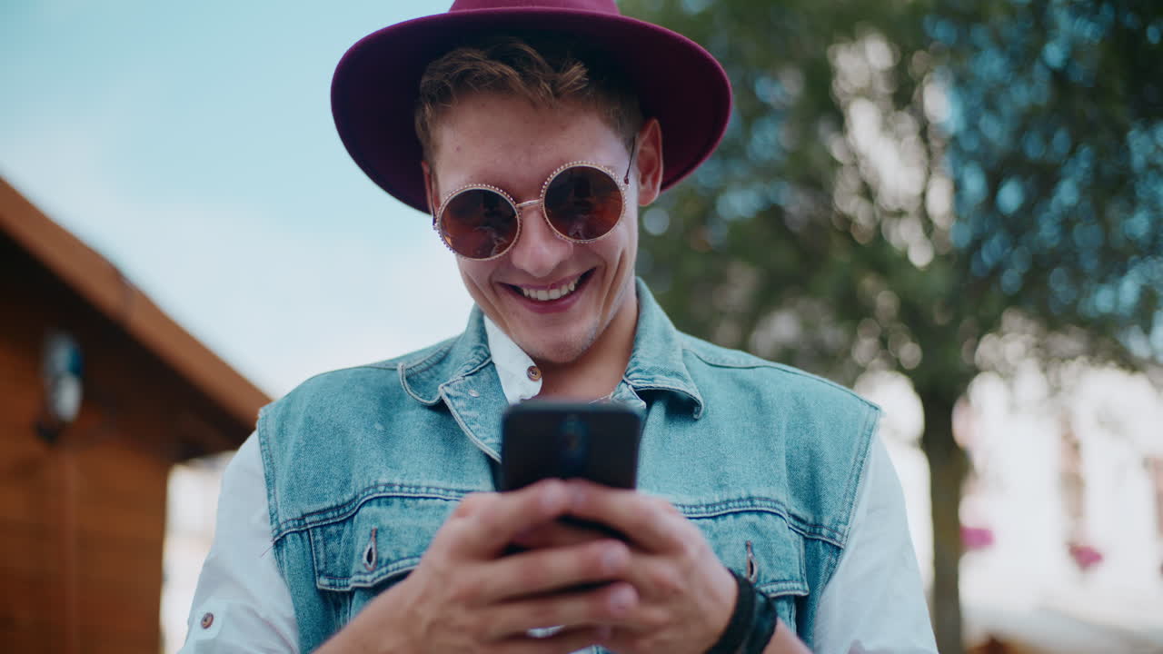 Uomo sorridente che manda un messaggio al telefono