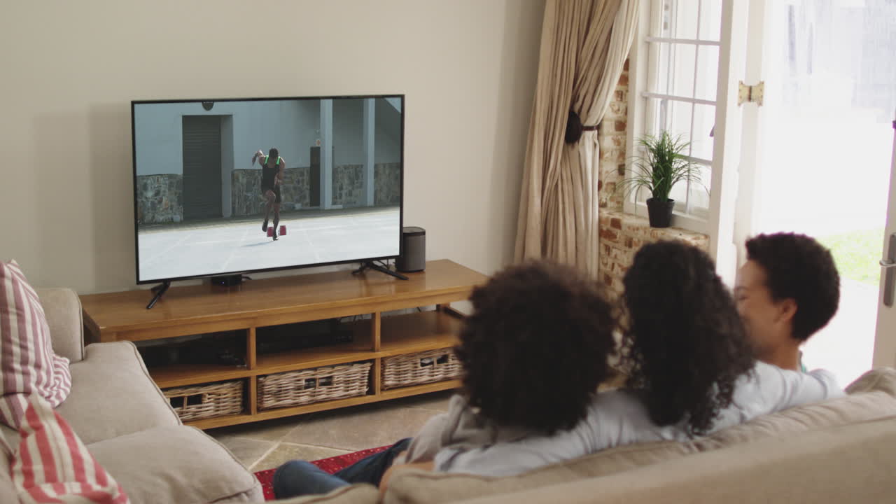 Famiglia felice seduta a casa insieme che guarda la corsa di atletica in TV