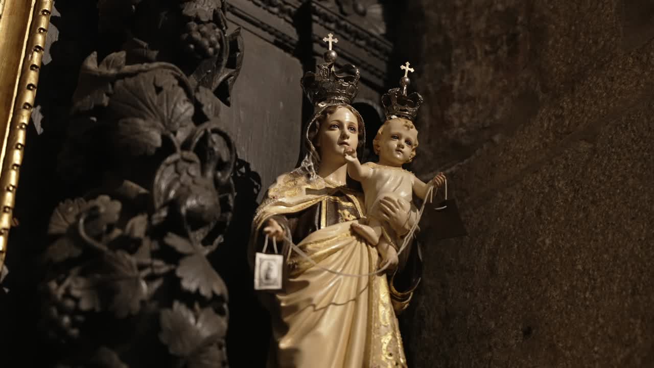 statue of crowned virgin mary with baby jesus holding scapulars in church