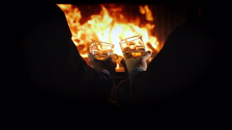 men with glasses of strong alcohol are resting by the fireplace winter escape