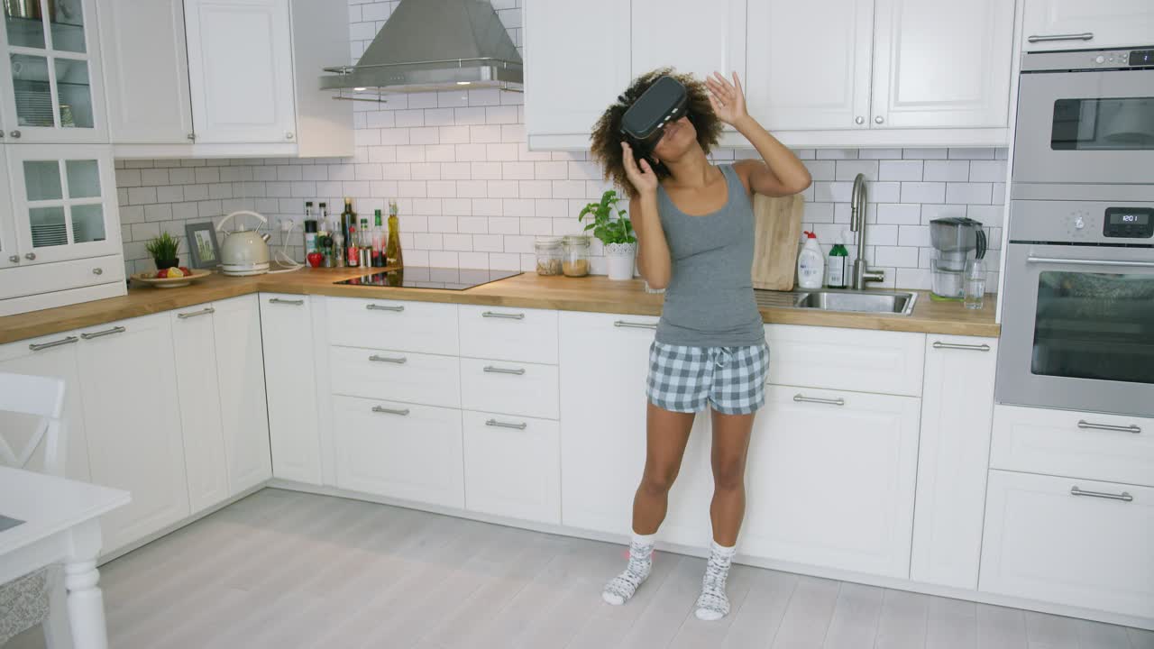 Donna con occhiali VR che balla in cucina