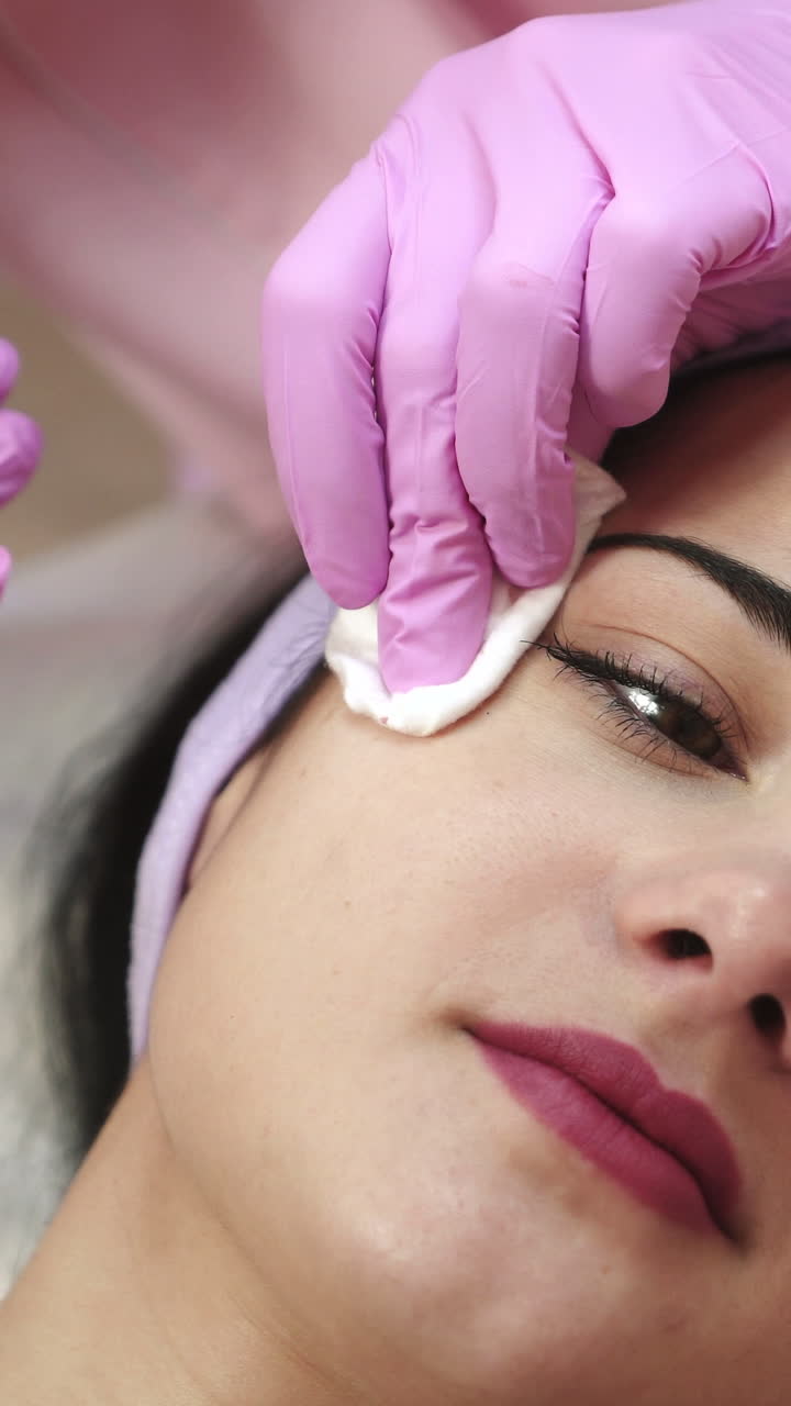 Young pretty woman receiving treatments in beauty salons. Young beautiful dark-haired woman in the office beautician lying on the couch. Contouring procedure , revitalization. Beauty injections . Vertical video