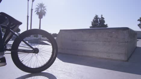 a bmx bike rider peddles out of frame at a skatepark