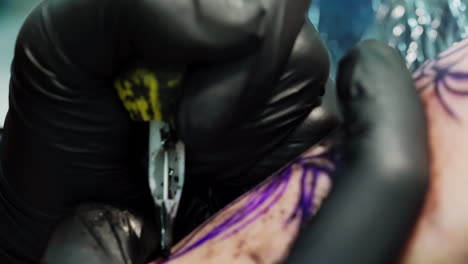 tattoo artist carefully draws a line with special ink machine. having a tattoo in a modern tattoo parlour. close up.