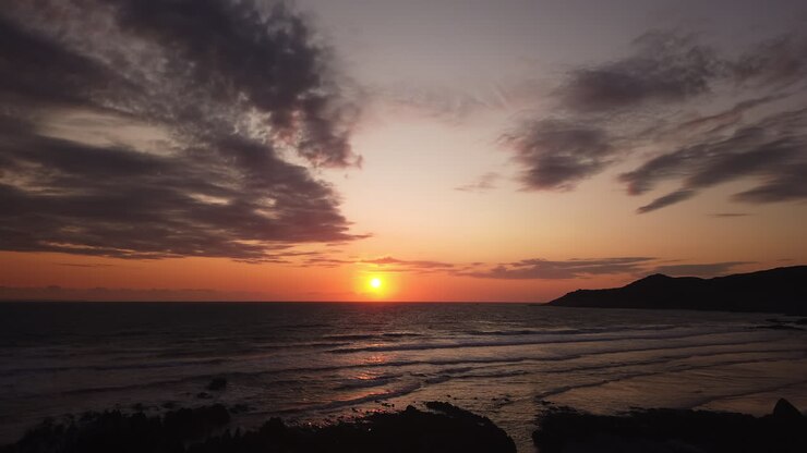 Sunset Motion Lapse of the Sun Setting over the Ocean with a Cargo Ship Crossing the Horizon