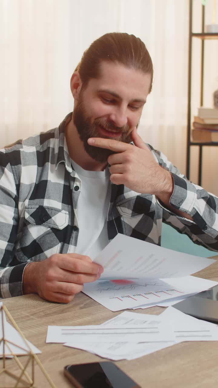 Giovane che controlla le bollette a casa tavola portatile dettagli sollievo sorriso calmo corrispondenza finanziaria accurata