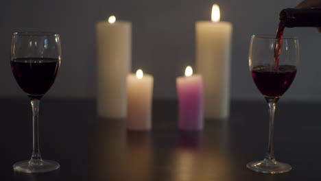 glass of red wine being poured at candle lit dinner table