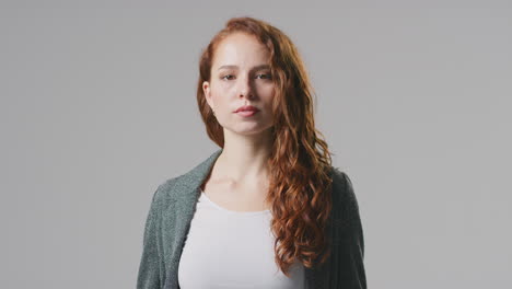 Studio-Portrait-Of-Serious-Young-Businesswoman-Folding-Arms-Against-Plain-Background