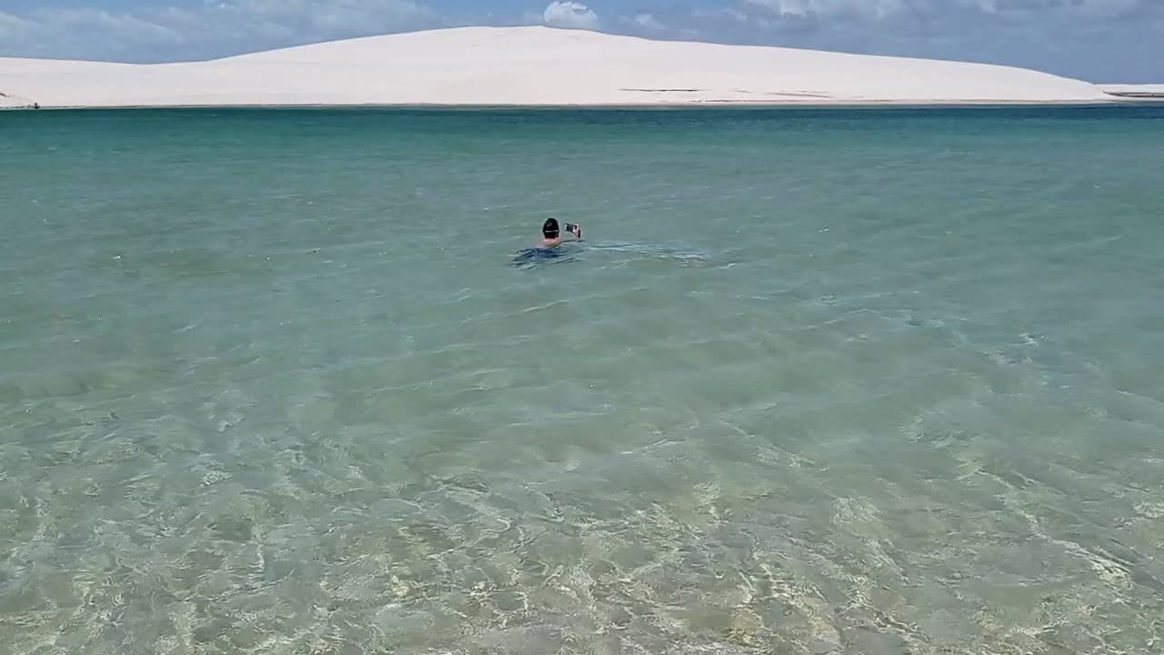 boy swimming on clear blue lagoon in Lencois Maranhenses national park, Brazil