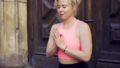 woman sitting in lotus pose in namaste over big wood door